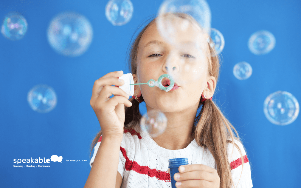 A young child blowing bubbles to strengthen speech muscles — a fun way to practice pronunciation.